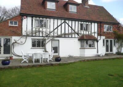 Tudor‑style home with diamond‑paned heritage metal windows, timber framing and a garden patio.