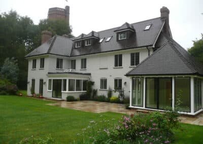 Large white heritage property featuring modern glass extensions alongside traditional metal‑framed windows and landscaped gardens.