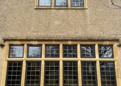 Exterior wall with upper and lower sets of grid‑patterned windows framed in stone on a classic building façade.